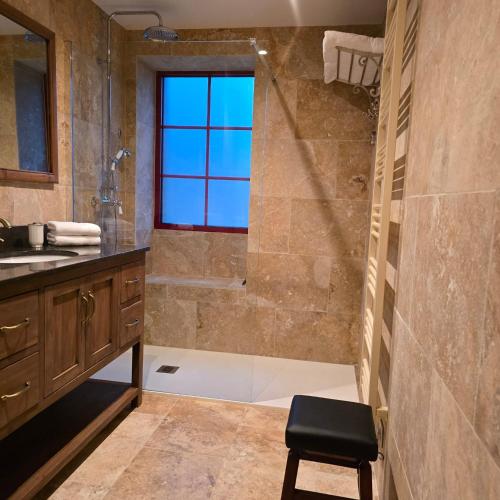 une salle de bain avec une douche, un lavabo et un tabouret dans l'établissement Le cottage Maisonnette dans corps de ferme, à Allainville