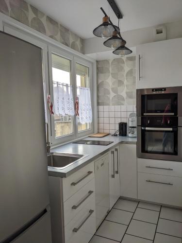 une cuisine blanche avec un évier et un micro-ondes dans l'établissement Appart spacieux 2 chambres, à Fort-Mahon-Plage