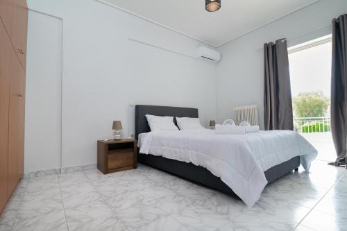 a white bedroom with a large bed and a window at The Sunrise Apartment By Athens Airport 1 in Spáta