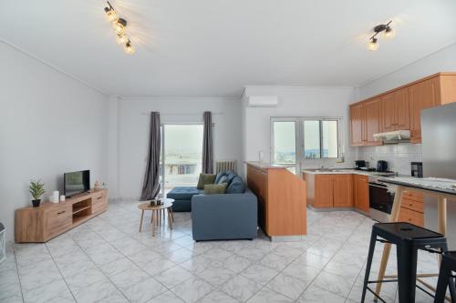 a living room with a blue couch and a kitchen at The Sunrise Apartment By Athens Airport 1 in Spáta