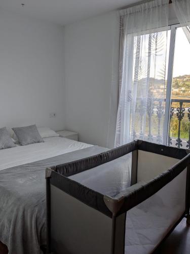a bedroom with a bed and a large window at Playa de Miño in Miño