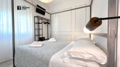 a bedroom with a bed with white sheets and towels at Hotel Nizza Creative Hotel in Rimini
