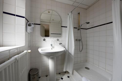 a white bathroom with a sink and a shower at Hotel De L'Europe in Toul