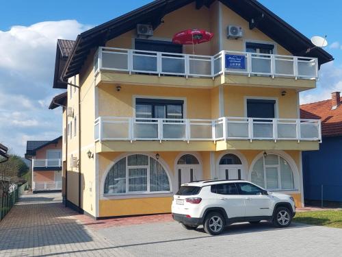 a white car parked in front of a yellow building at Urban home apartments in Bihać