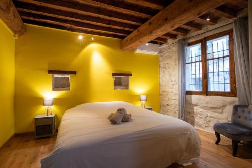 une chambre avec un lit blanc et un mur jaune dans l'établissement Marmandin - Clim - Proche Arènes, à Arles