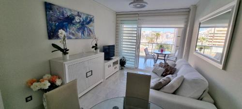 een woonkamer met een bank en een tv bij Magic holiday - 1st line, seaview, pool & parking in Ifach