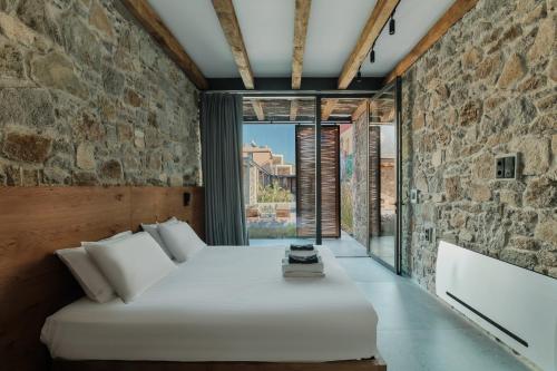 スカラ・エレソスにあるBarefoot Luxury Eressos Apartmentsの石の壁の中にベッドが置かれた寝室