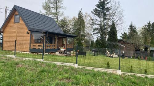a log cabin in a field with a fence at Uroczy domek nad Gilem in Miłomłyn