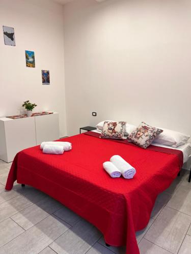 Un dormitorio con una cama roja con toallas. en La casa di Giorgia, en Catania