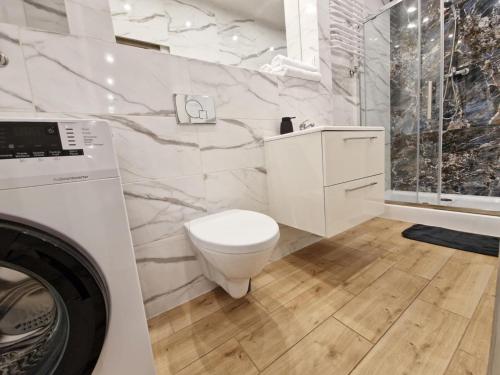a white bathroom with a toilet and a shower at Kielce City Center Paderewskiego 24 in Kielce