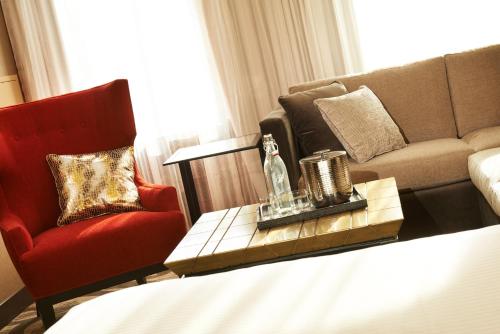 a living room with a red chair and a couch at Metropolitan at The 9, Autograph Collection in Cleveland