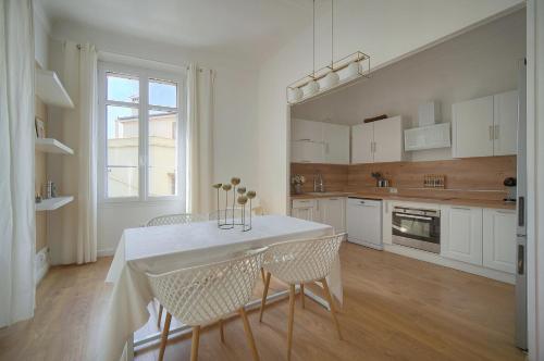 une cuisine avec une table et des chaises dans une pièce dans l'établissement Sublime appartement luxe T3 incroyable Jardin Plein cœur Cannes, à Cannes