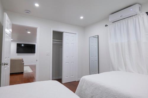 a white bedroom with two beds and a flat screen tv at Modern Retreat Poconos 3BR Fire Pit Skiing in East Stroudsburg
