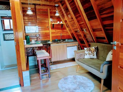 a living room with a couch and a kitchen at Chalé Família Rigolo 1 Anthony in Monte Verde