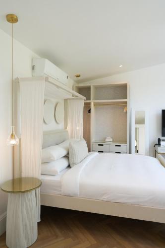 a bedroom with a large white bed and a table at âmé by NOAH in Cape Town