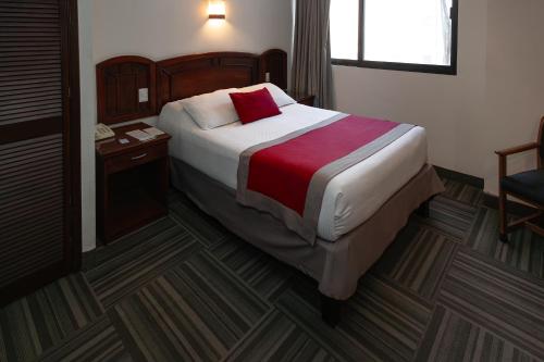 a hotel room with a bed and a desk with a phone at Ramada Plaza by Wyndham Leon in León
