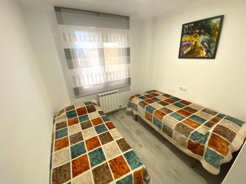 two beds in a small room with a window at Apartamento Ponent Stays in Almacellas