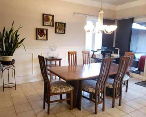 a dining room with a wooden table and chairs at La campagne en ville avec spa in Laval