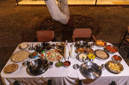 a table with many plates of food on it at Brook Ville in Sasan Gir
