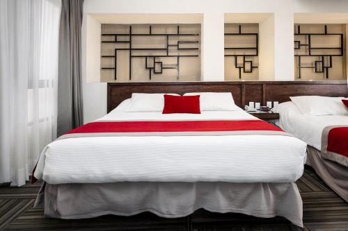 a bedroom with two beds with red pillows at Ramada Plaza by Wyndham Leon in León