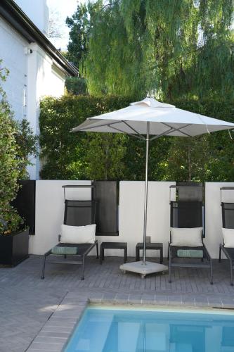 an umbrella and chairs next to a swimming pool at âmé by NOAH in Cape Town