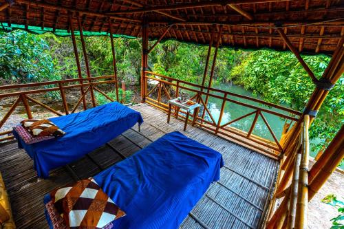 a porch with two beds and a view of a river at Brook Ville in Sasan Gir