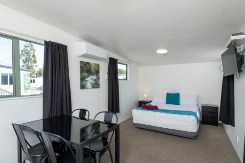 a bedroom with a bed and a table and a desk at Riverside Whakatane Holiday Park in Whakatane