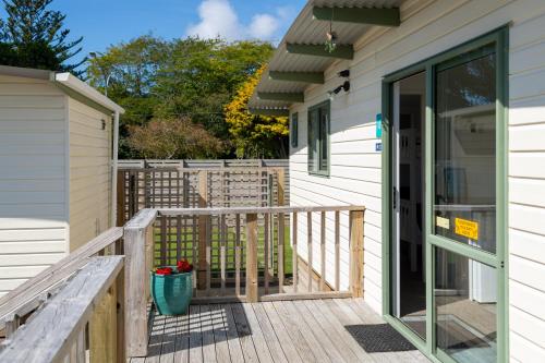 a house with a wooden porch with a door at Riverside Whakatane Holiday Park in Whakatane