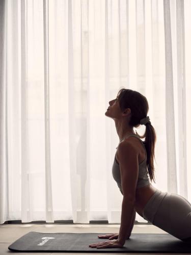 a woman doing a yoga pose in front of a window at Bond Smart Living Suites in Athens