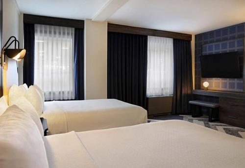 a hotel room with two beds and a flat screen tv at The Brock Niagara Falls Fallsview, Tapestry by Hilton in Niagara Falls