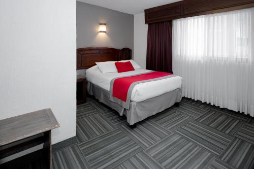 a bedroom with a bed with a red blanket at Ramada Plaza by Wyndham Leon in León