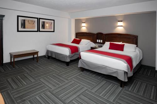 a hotel room with two beds with red pillows at Ramada Plaza by Wyndham Leon in León
