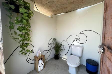 a bathroom with a toilet and plants on the wall at The Baja Station - Beachfront Surf Lodge in La Palmilla