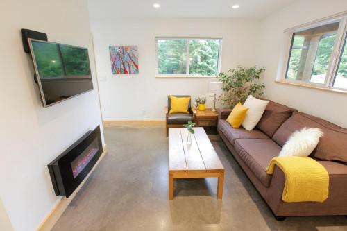 a living room with a brown couch and a tv at Tidal Retreat Cabin in Tofino