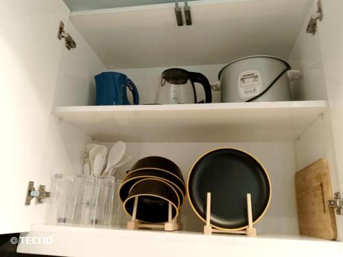 a kitchen shelf with plates and other kitchen utensils at Studio 7 Residential Building in Manila