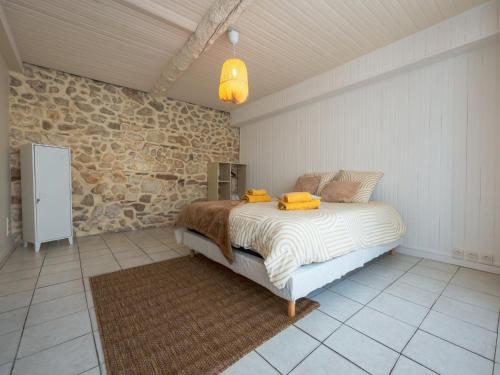 une chambre avec un lit et un mur en pierre dans l'établissement La Cuxanaise, à Cuxac-dʼAude