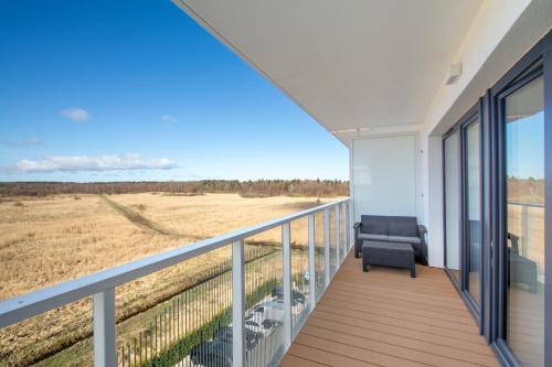 a balcony with a couch and a view of a field at Klif Apartamenty Polanki Aqua in Kołobrzeg