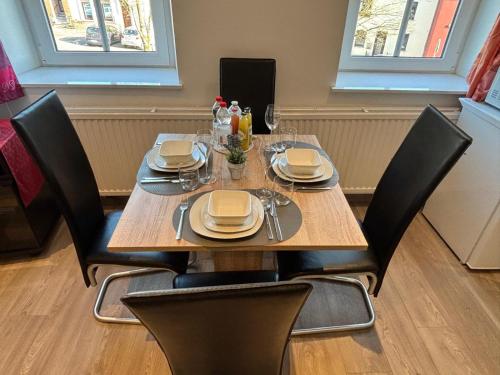 a wooden table with black chairs and plates on it at PlanetOase Eupen in Eupen