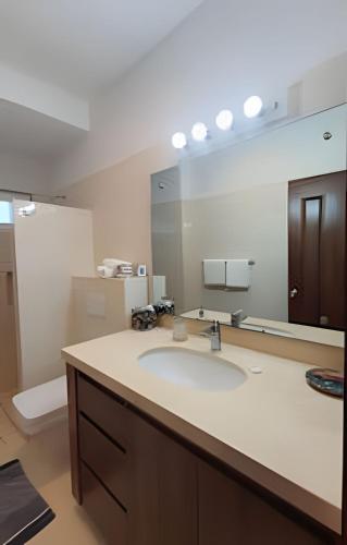 a bathroom with a sink and a large mirror at Departamento Mauricio #2 in Bucerías