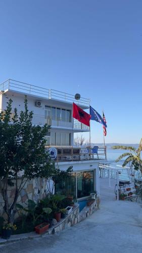 a hotel on the beach with a flag at Vila Rahmi & Veli Dervishaj in Vlorë
