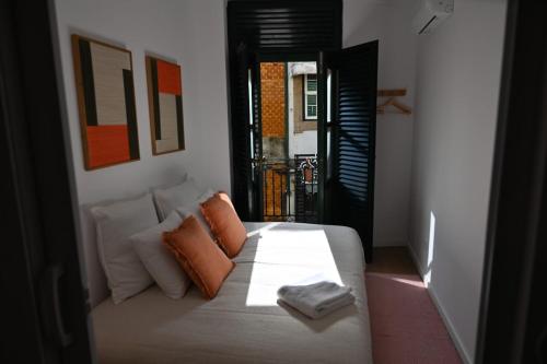 a bedroom with a white bed with orange pillows at Downtown Lovely in Vila Real