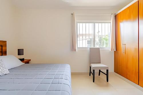 a bedroom with a bed and a chair and a window at Departamento Mauricio #3 in Bucerías
