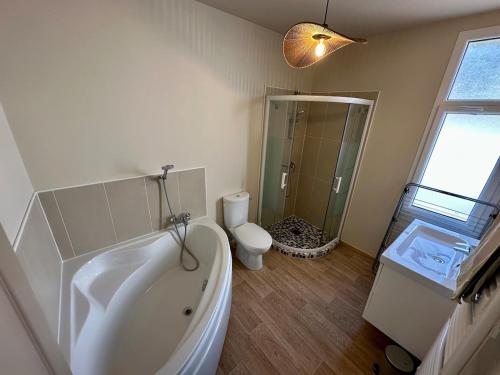 La salle de bains blanche est pourvue d'une baignoire et de toilettes. dans l'établissement L'Ecluse de Louise, VUE SUR BAIE, à Saint-Valery-sur-Somme