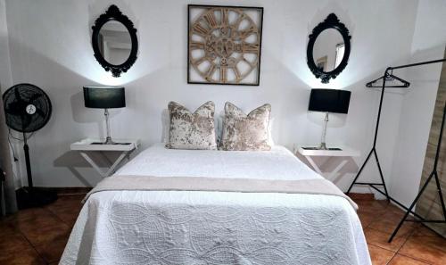 a bedroom with a bed with two mirrors on the wall at Zhantique Guest House 1- Unit 4 in Boksburg