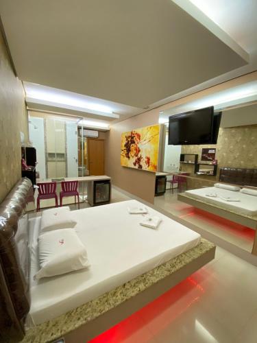 a bedroom with a large white bed and a tv at Rodotel Venus (Adults Only) in Jataí