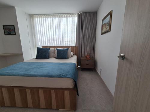 a bedroom with a bed with blue sheets and a window at Belmonte207-Hermoso apartamento de lujo con aire acondicionado in Armenia