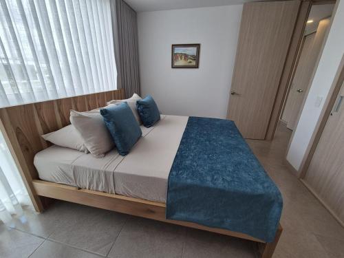 a bedroom with a large bed with blue pillows at Belmonte207-Hermoso apartamento de lujo con aire acondicionado in Armenia