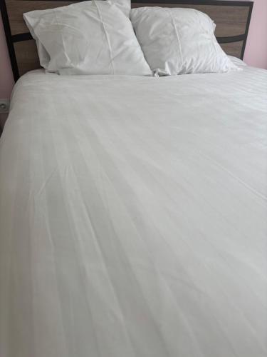 d'un lit non aménagé avec des draps et des oreillers blancs. dans l'établissement Maison à 10m de Porto Vecchio centre, à Sotta