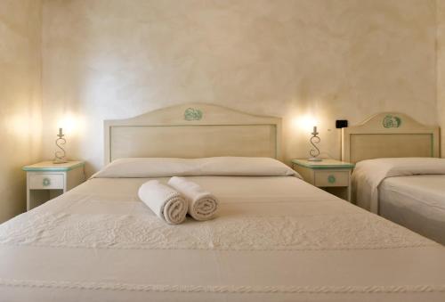 um quarto com duas toalhas brancas numa cama em Morpheo Rooms em Alghero