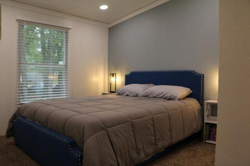 a bedroom with a bed with a blue headboard and a window at Cute Shawnee Twin Lakes home sleeps 10&has it all! in Shawnee